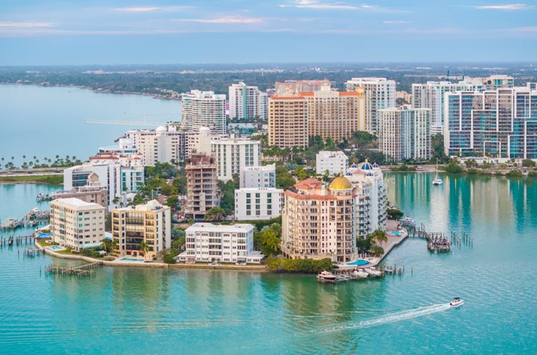 Aerial view of coastal condo buildings and the surrounding Gulf waters in Sarasota, Florida.