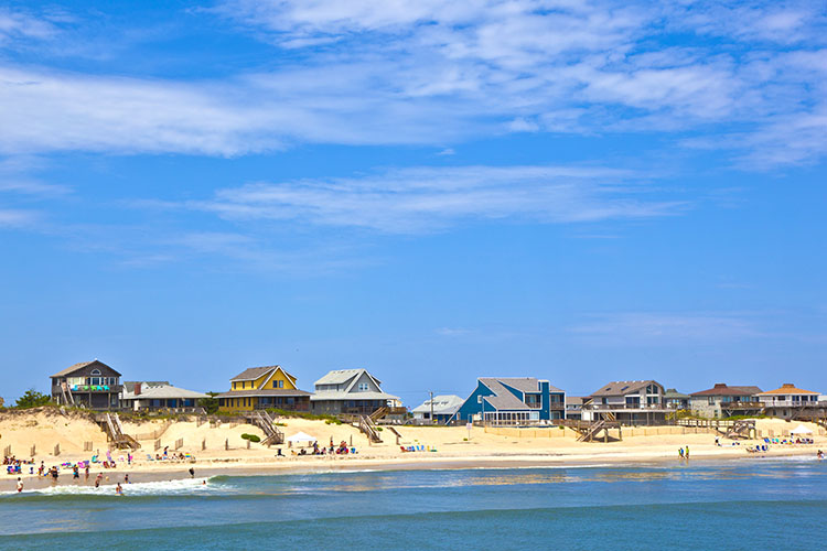 Nags Head, NC beach, with homes and beachgoes along the water