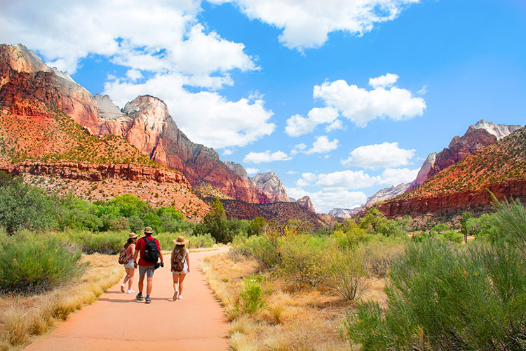 A father and his two daughters walking down a trail in Zion National Park