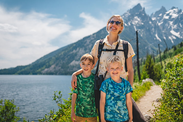 A mother and her two young sons smile at Jenny Lake in Wyoming