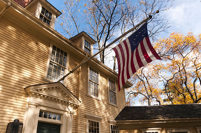 A home in Lexington Massachusetts with an American flag hanging in the front of the home. 