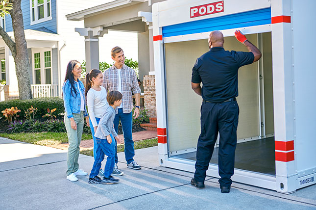 A family looks on as their PODS driver closes the door to their container as they move to their new Boston suburb