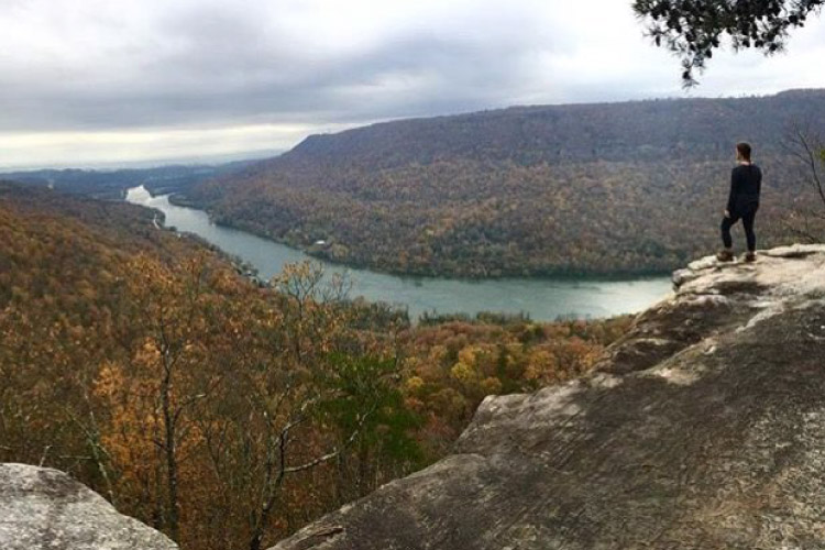 A woman is standing on Edward’s Point on Signal Mountain in Tennessee, looking out over Walden’s Ridge and the river below.