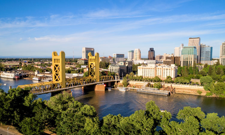 Aerial view of Sacramento, California, including Tower Bridge and the Sacramento River, on a sunny summer day.