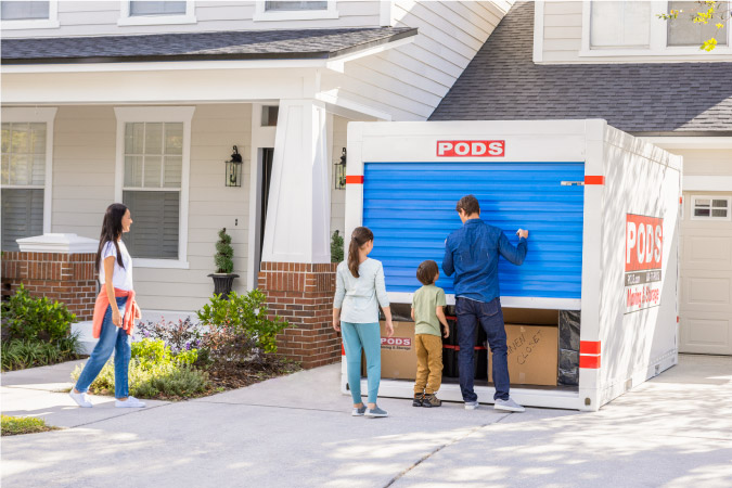 A family of four prepares to unload their PODS portable moving container in the driveway of their new home in one of the cities near Atlanta, GA