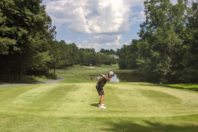 A golfer is poised mid-swing while playing a round of golf in Tega Cay, South Carolina.