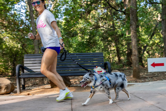 A woman and her dog are running through a park in Mansfield, Texas, during a community event.