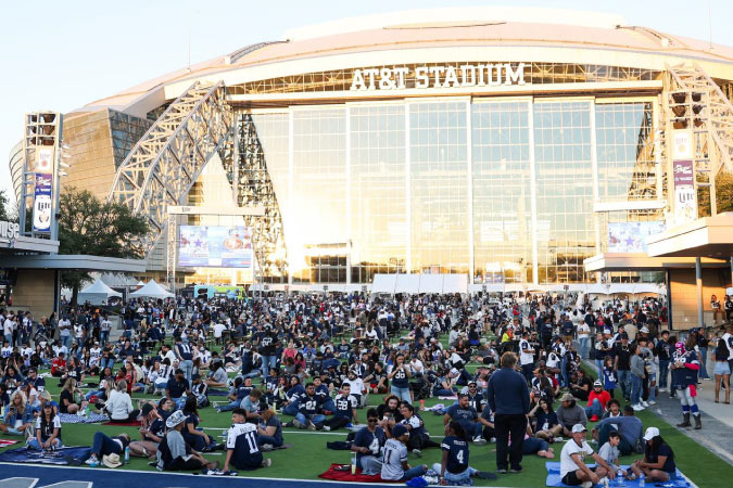 Hundreds of Cowboys football fans gather on the lawn outside AT&T Stadium in Arlington, Texas.