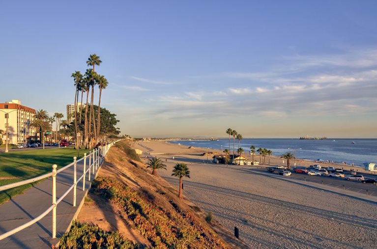 View of a beach parking lot, condos, and a seaside park in Long Beach, California.