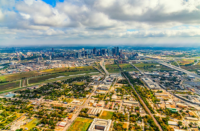 The skyscape of Dallas, with a residential neighborhood in the foreground. You can see downtown in the distance.