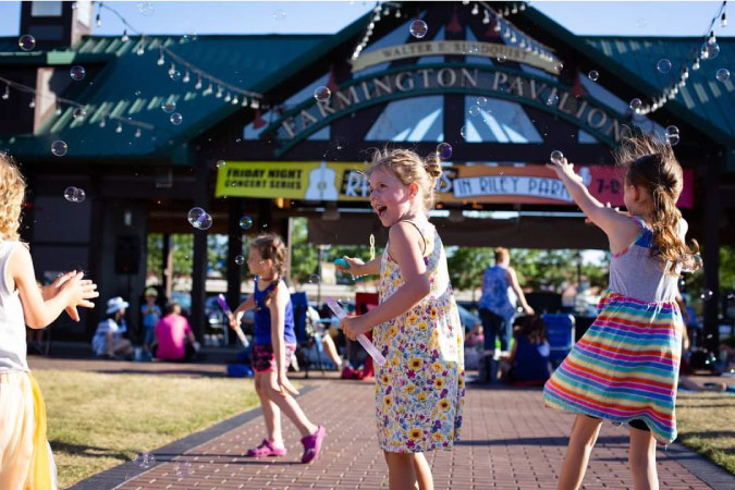 Young girls are using bubble wands to blow bubbles during a community event in Farmington, Michigan