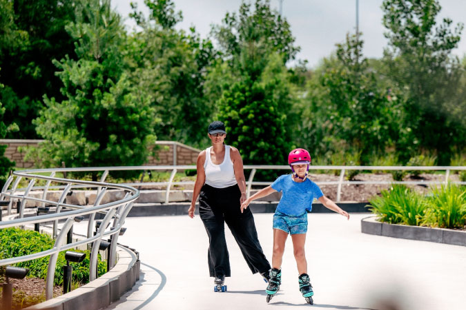 A mother on rollerskates follows just a few feet behind her young daughter who is rollerblading in a city park in Troy, Michigan.