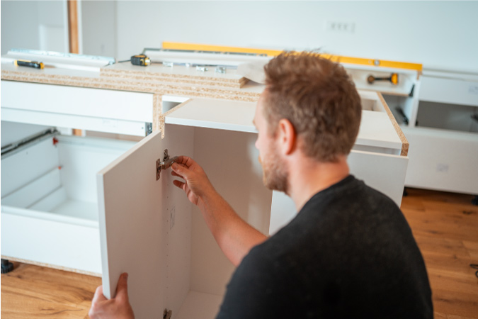 A man is installing a new set of cabinets during his DIY kitchen remodel