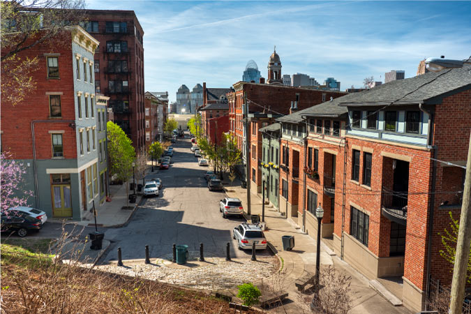 Historic buildings in the Over-The-Rhine neighborhood of Cincinnati, Ohio, featuring row houses and a glimpse of the city in the background.