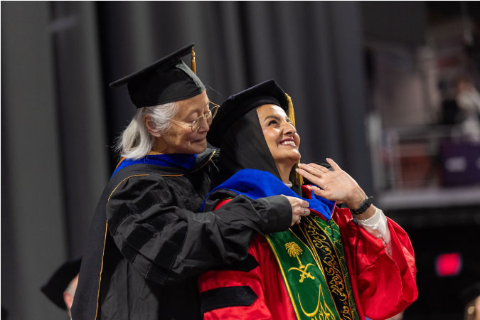 A recent graduate of the University of Cincinnati beams proudly as her professor awards her an accolade