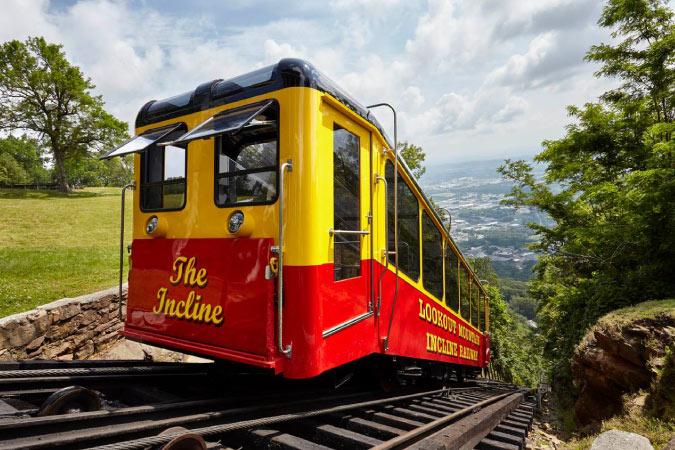 An iconic red and yellow Incline Railway car is climbing up the side of Lookout Mountain outside Chattanooga.