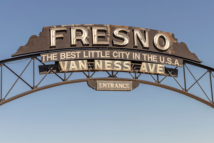 A metal sign that reads “Fresno, the best little city in the USA,” hanging over Van Ness Avenue