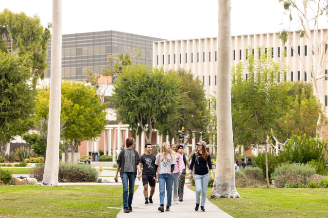Students walk along a path on the campus of California State University, Long Beach, on a sunny day.
