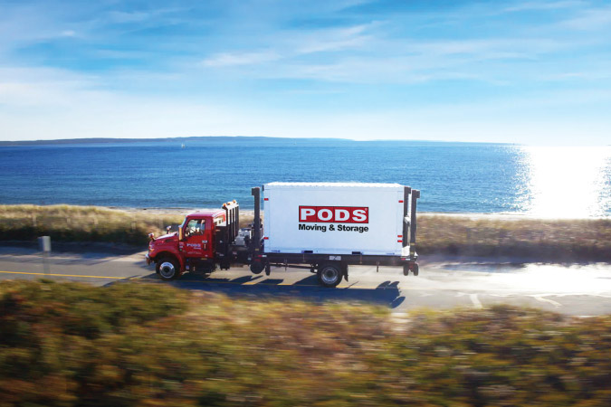 A PODS truck is transporting a portable moving and storage container along the California coast to Long Beach.