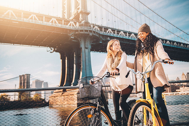 Two friends ride bikes along the East River in New York City