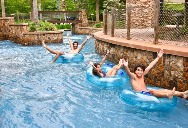  A family of three pose with their arms outstretched as they tube down the lazy river at Forest Oasis Water Park in The Woodlands, Texas. 