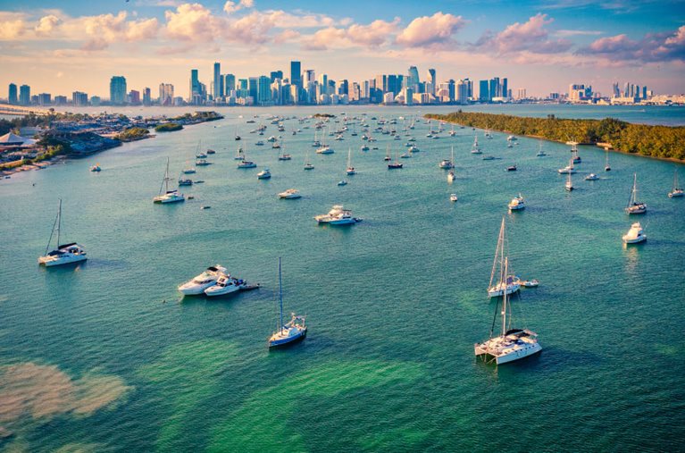 Distant view of the Miami skyline over sailboat dotted waters.