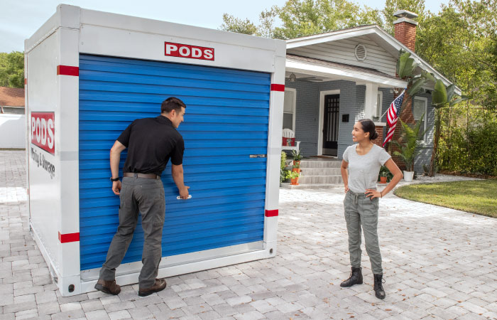 A soldier and his family are loading boxes and other things into one of two PODS containers during their military move.