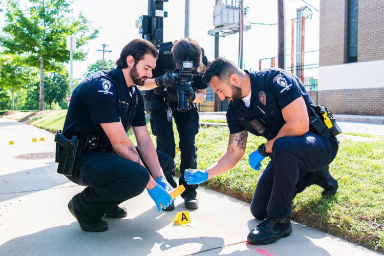 Officers for the Charlotte-Mecklenburg Police Department in North Carolina document evidence at a crime scene.