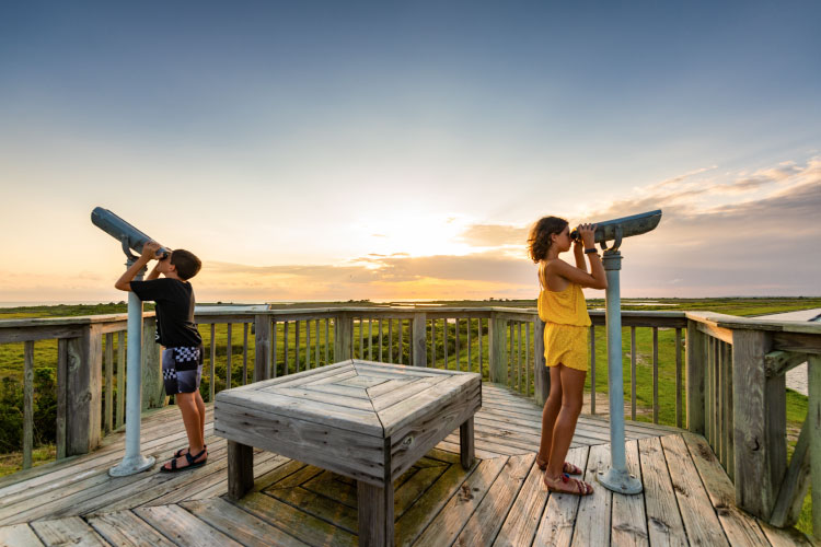 Two kids look through stationary tower viewers at Pea Island National Wildlife Refuge in Rodanthe, North Carolina.