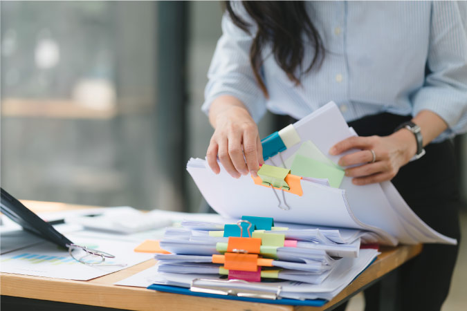 Close-up of a woman going through paperwork on her desk