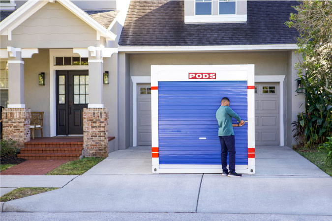 A young man is unlocking the PODS portable storage container in his driveway 