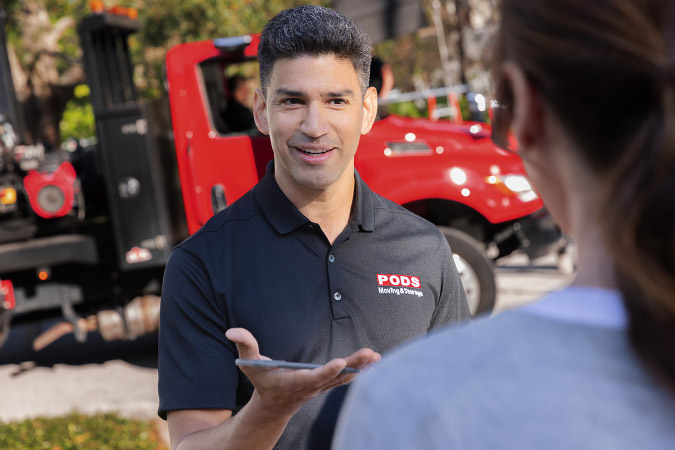A PODS driver is speaking with a member of the military during her partial DITY move. There is a PODS truck in the background.