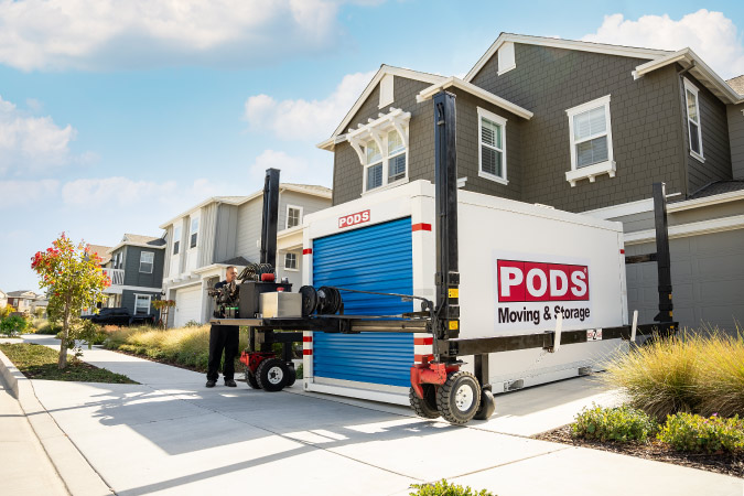A PODS driver is using PODZILLA to position a PODS moving container in a residential driveway for a member of the military during their PPM.