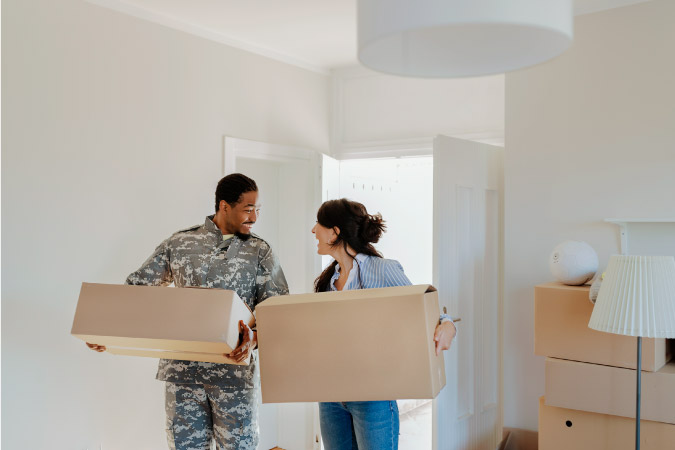  A soldier and his wife are carrying moving boxes into their new home during their DITY PCS move.