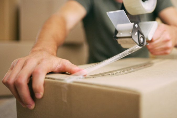 Close-up of a soldier sealing a moving box with packing tape during his PCS move.