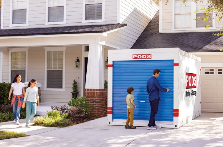 A family of four is checking out the PODS portable moving container in their driveway.