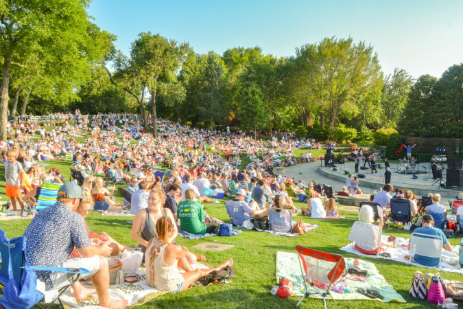 Hundreds of Dallas locals gather for an outdoor concert at the Dallas Arboretum on a sunny summer day