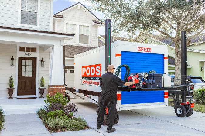 A PODS driver is using PODZILLA to position PODS portable moving container in a residential driveway