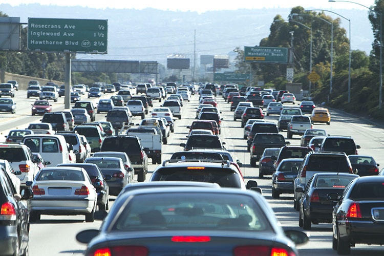 Four lanes of bumper-to-bumper traffic in Los Angeles. There are green signs indicating the distance to separate exits. 