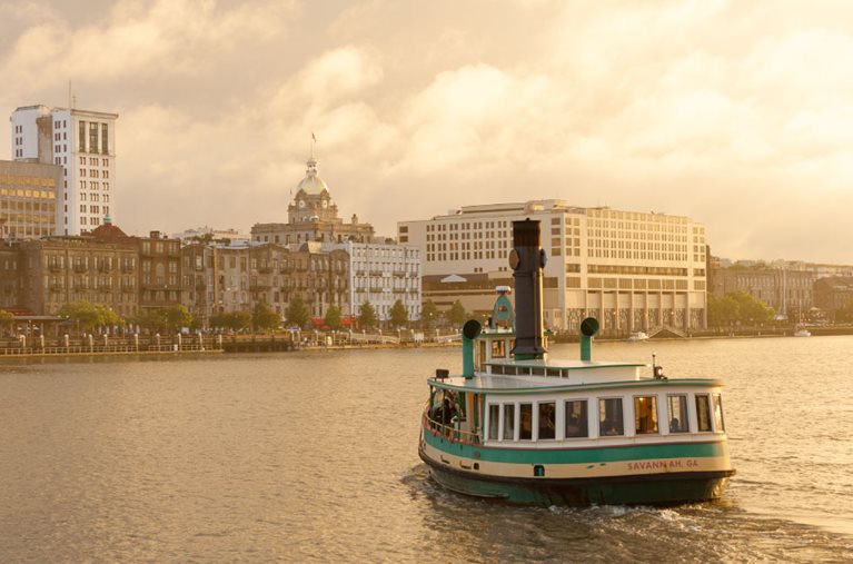 A ferry is crossing the water toward historic Savannah, Georgia, in the early morning.