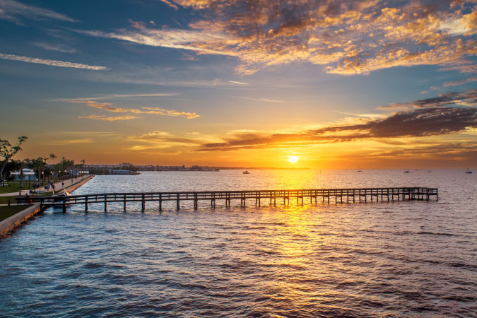 Sunset over Peace River in Punta Gorda’s Gilchrist Park, featuring a horizon dotted with moored sailboats.