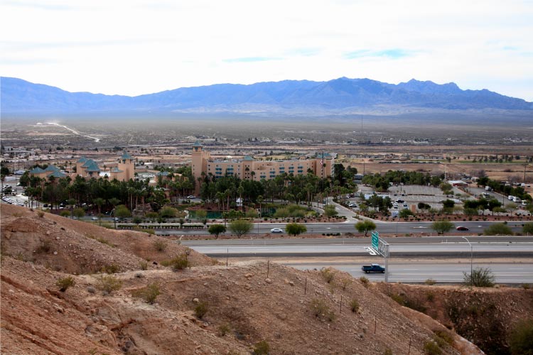 Distant view of Mesquite, Nevada, seen from across Highway I-15. Mesquite is a little oasis near the Arizona/Nevada border. The mountains in the distance, beyond the town, create a distinct silhouette against a bright sky.