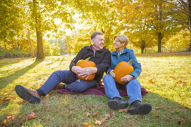 A retired company enjoys a Pennsylvania autumn, sitting in the woods holding pumpkins
