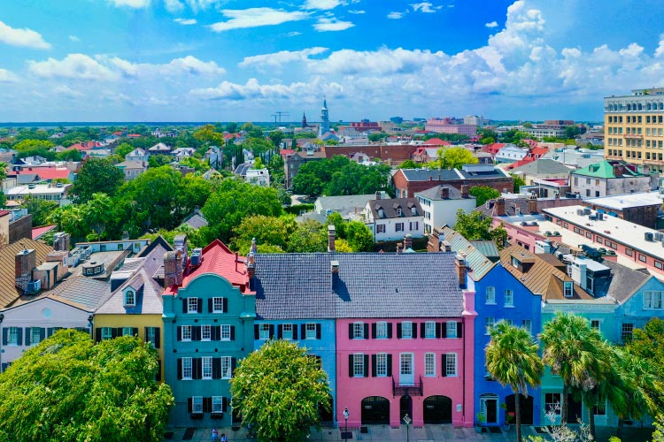 Aerial view of Charleston, South Carolina, with Rainbow Row in the foreground. It’s a sunny day, making the colors of the buildings and the trees pop with vibrancy.