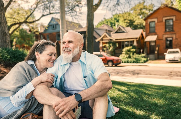 A recently retired senior couple shares a loving moment together on a grassy lawn in their new neighborhood in Toronto, Canada.