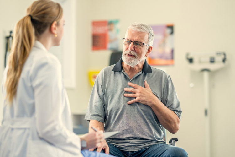 A senior man is sitting in an exam room and speaking with his doctor during a medical appointment in Canada. 