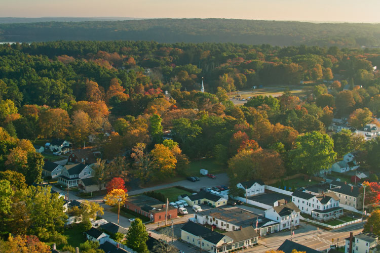 Aerial view of Scituate, Rhode Island, in the early fall. Most of the buildings are painted white, and only a few trees have begun to change colors.