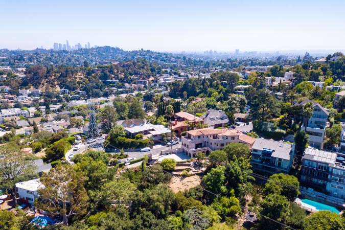 Aerial view of Los Feliz — one of the safest neighborhoods in Los Angeles — on a sunny day, featuring the Downtown skyline in the distance.