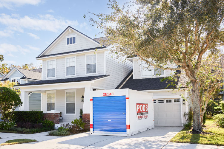 A PODS portable moving and storage container is positioned conveniently in the driveway of a two-story home in Tampa, Florida.