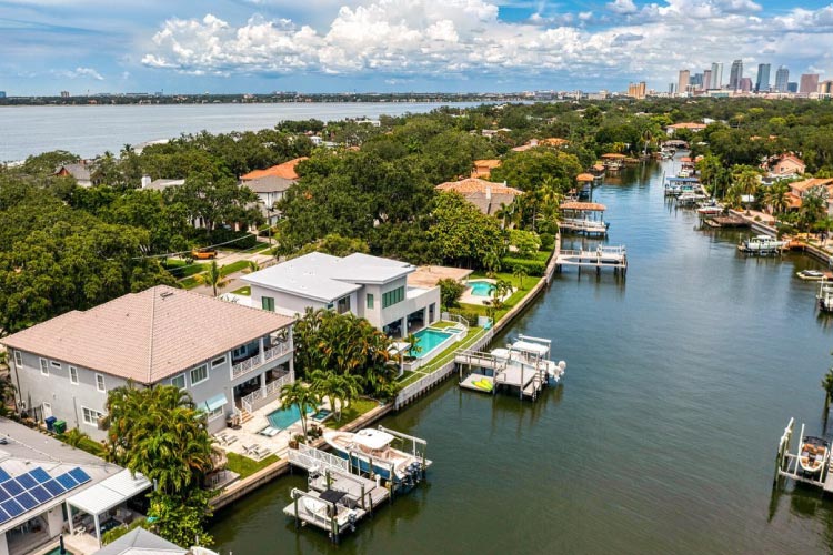 Aerial view of luxury waterfront mansions in the Davis Islands neighborhood of Tampa, Florida. The Tampa skyline is visible in the distance. 